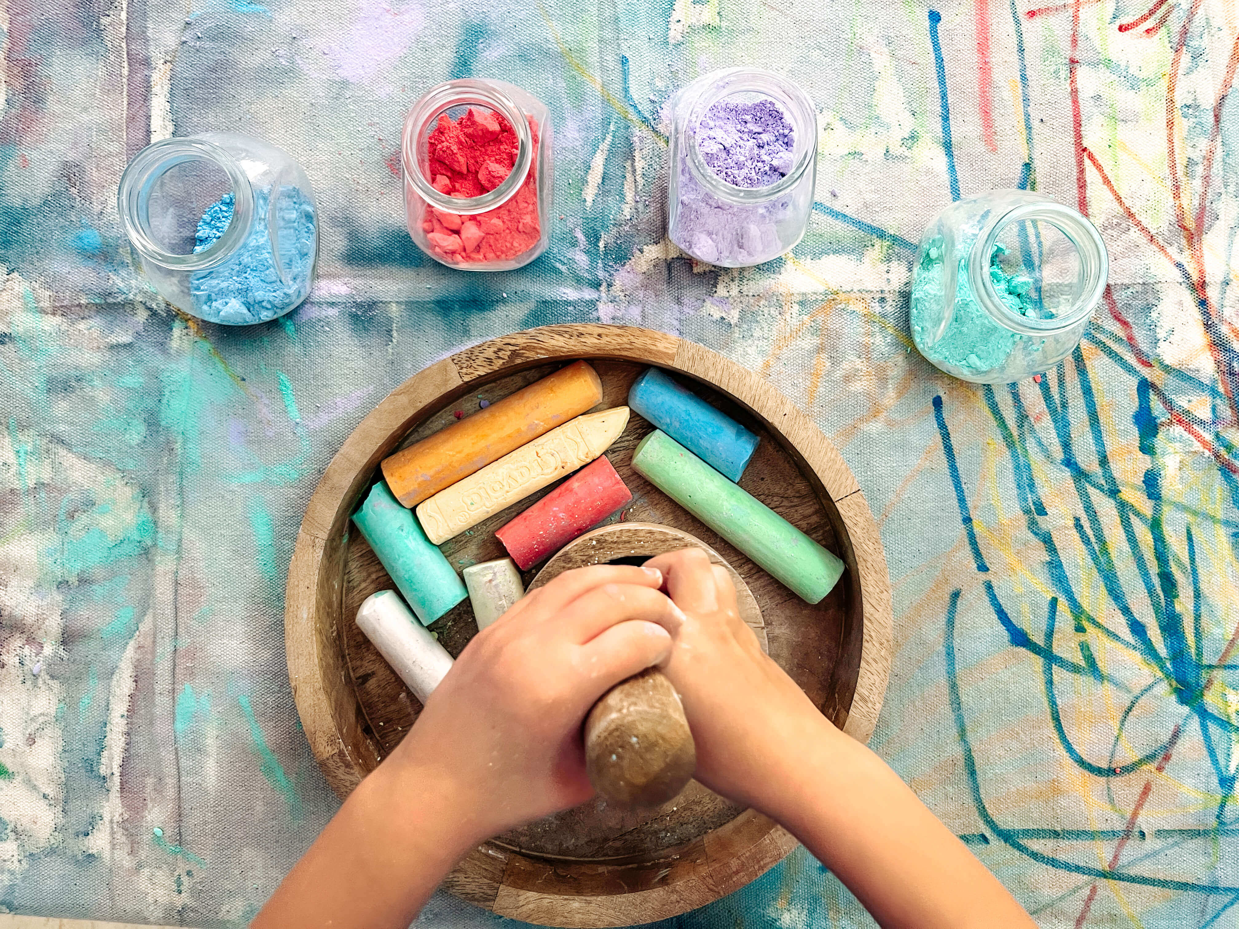 A child holding a mortar and pestle while crushing chalk