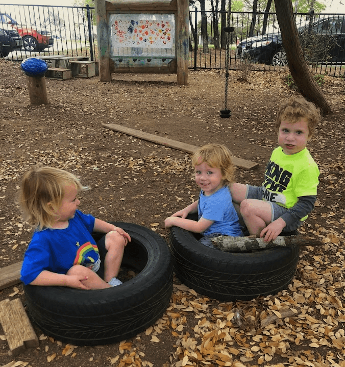 Children outside sitting on tires